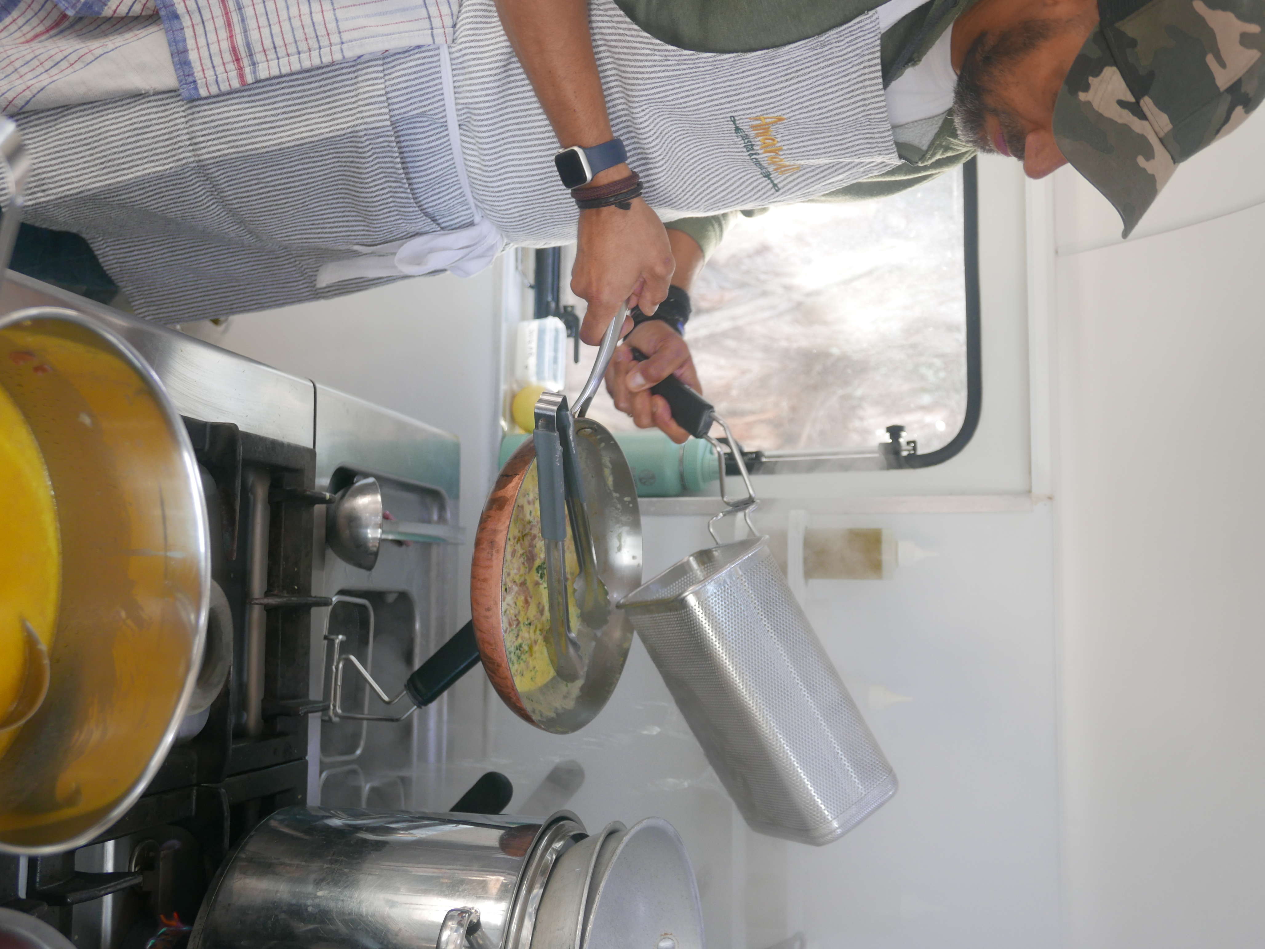 Tommaso cooking fresh gluten-free pasta in the Amaranto vintage caravan kitchen, wearing his Amaranto apron