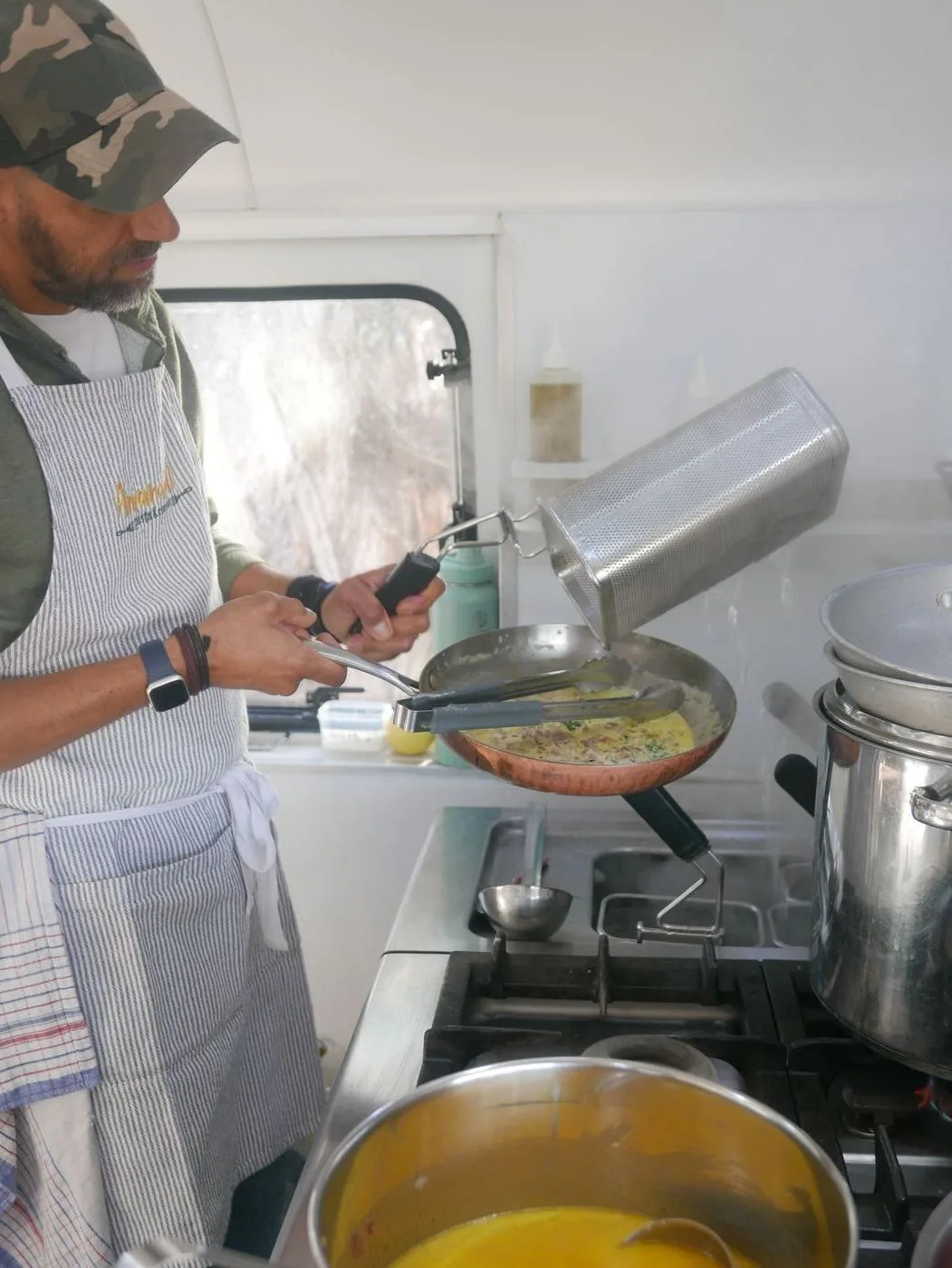 Tommaso cooking fresh gluten-free pasta in the Amaranto vintage caravan kitchen, wearing his Amaranto apron