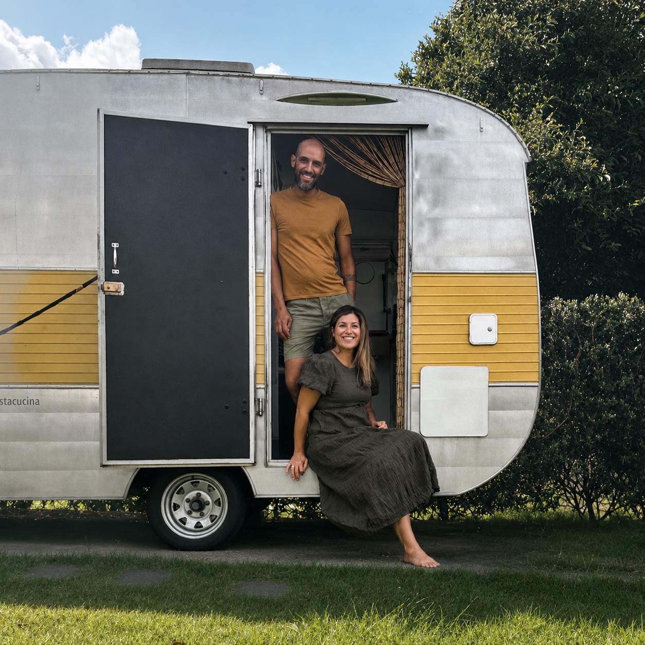 Tommaso and Luisa, founders of Amaranto, smiling in the doorway of their vintage Italian food truck caravan in Auckland