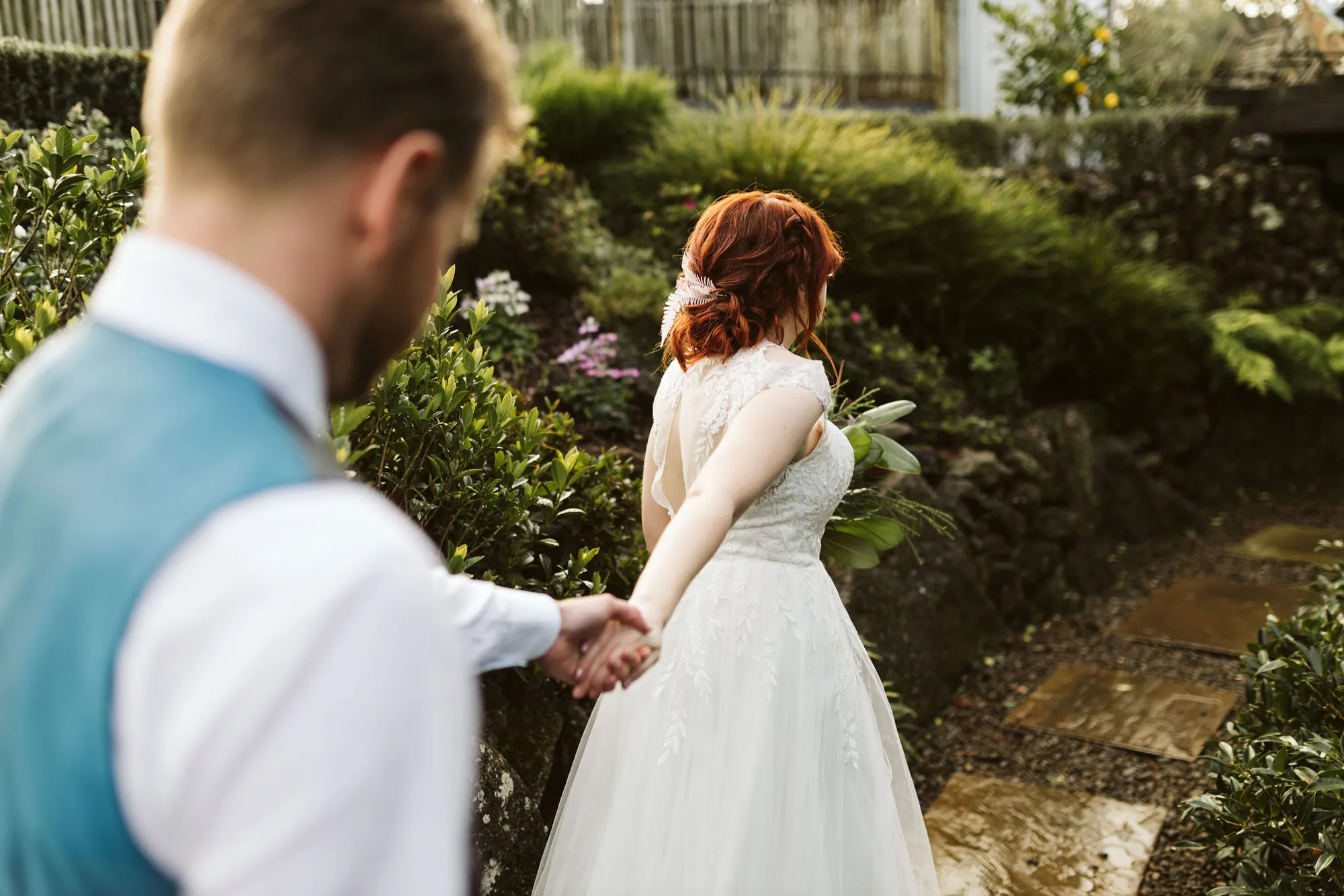 Vince leading Amy by the hand through a garden path after the ceremony