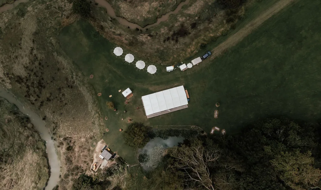 Aerial view of Waterfall Farm in Kaukapakapa — rolling hills, lily pond and the red barn, venue for Andrew and Laura's wedding