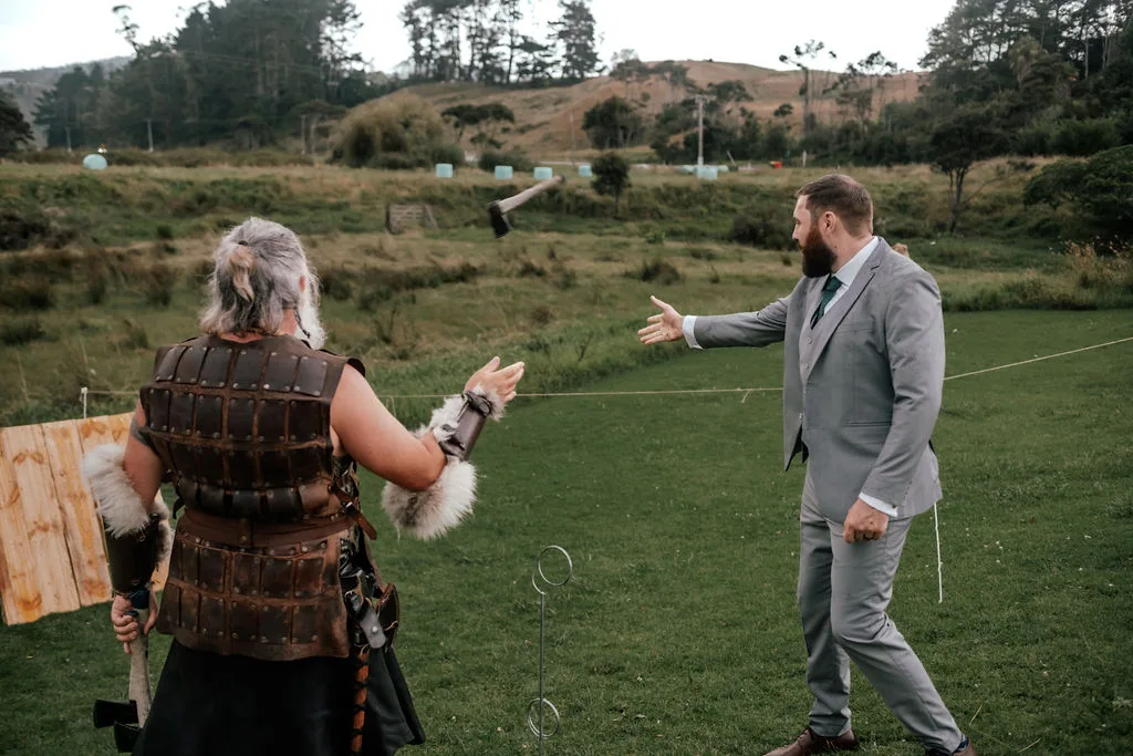 The groom throws an axe with a fully costumed Viking during the cocktail hour activities at Waterfall Farm