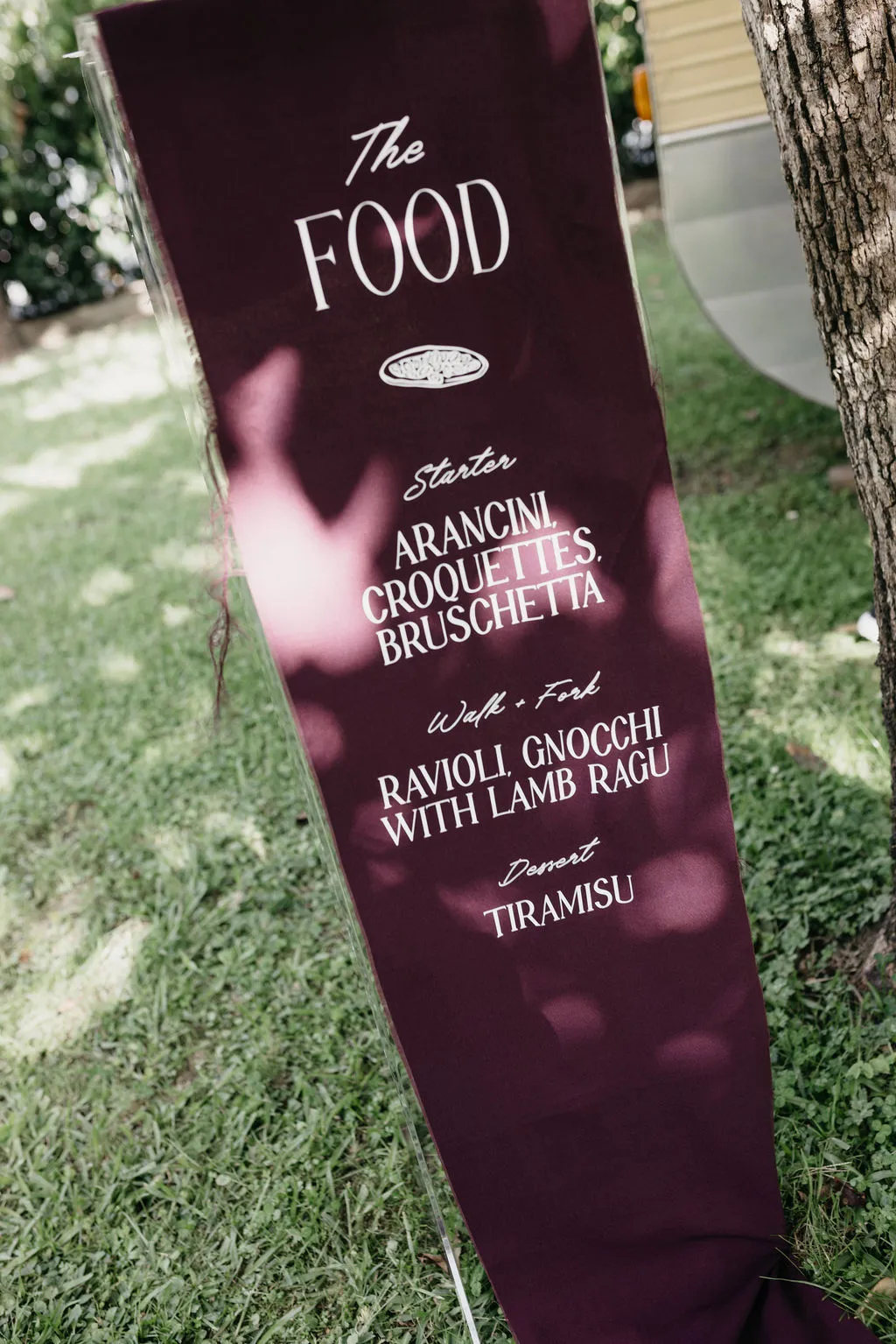 Close-up of the food menu sign at Chloe and Mitchell's wedding — arancini, croquettes and bruschetta, ravioli and gnocchi with lamb ragù, and tiramisu