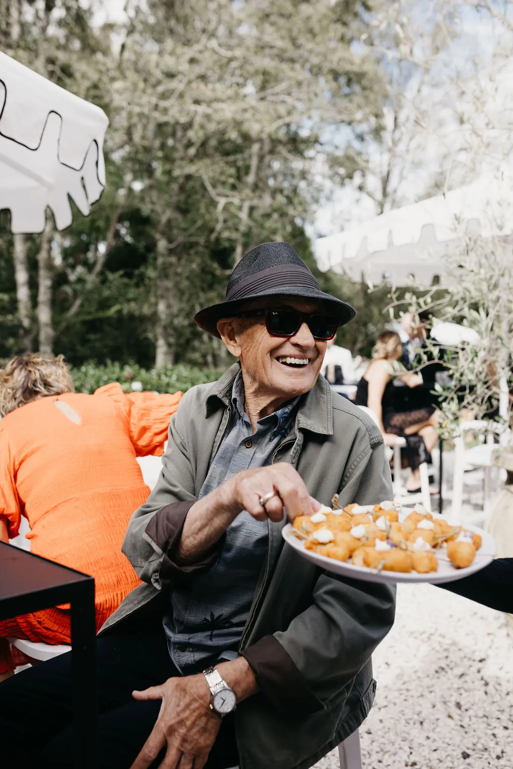 A delighted guest reaching for arancini from a passing canapé plate at Chloe and Mitchell's wedding
