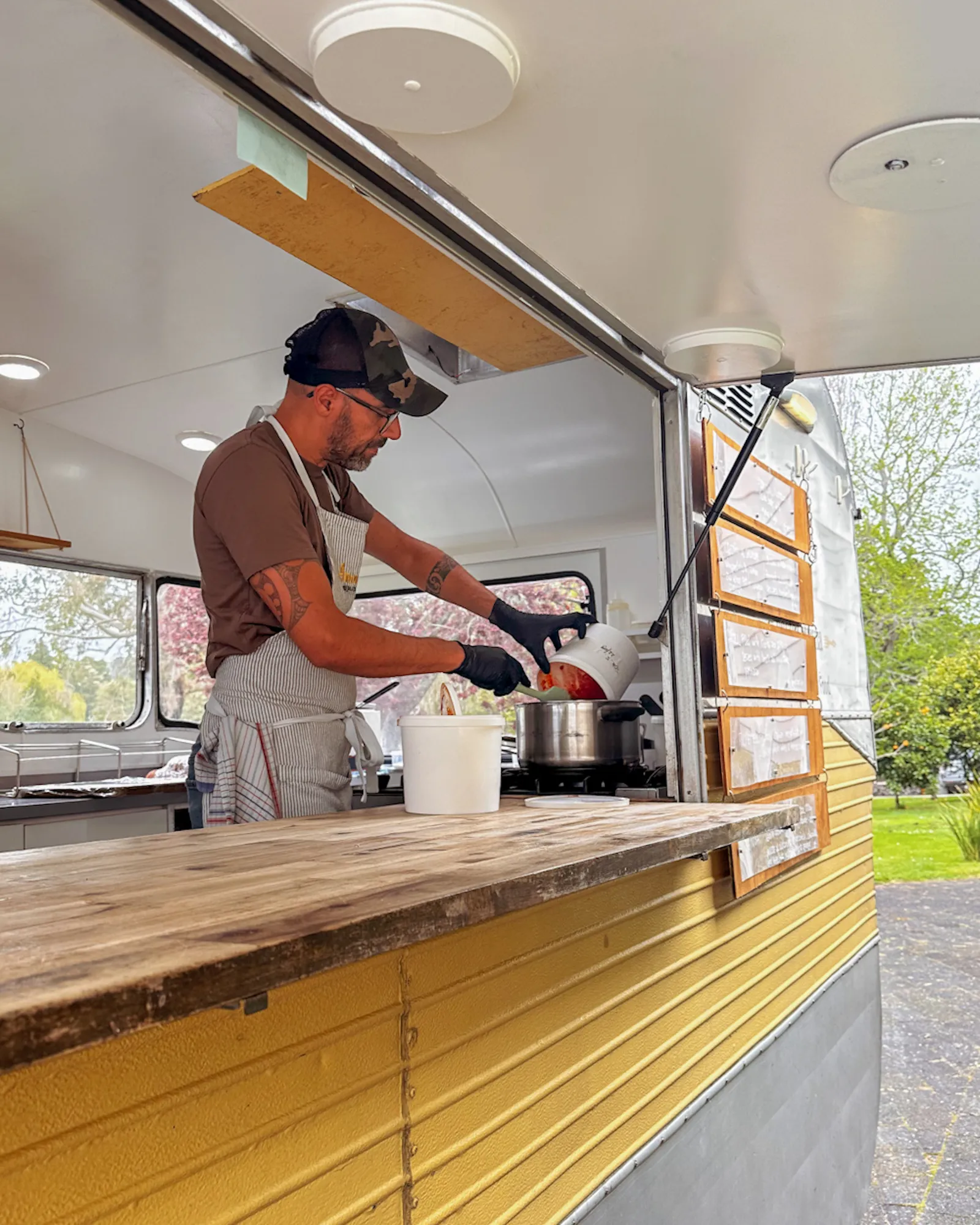 Tommy cooking tomato sauce inside the Amaranto caravan before a wedding service.