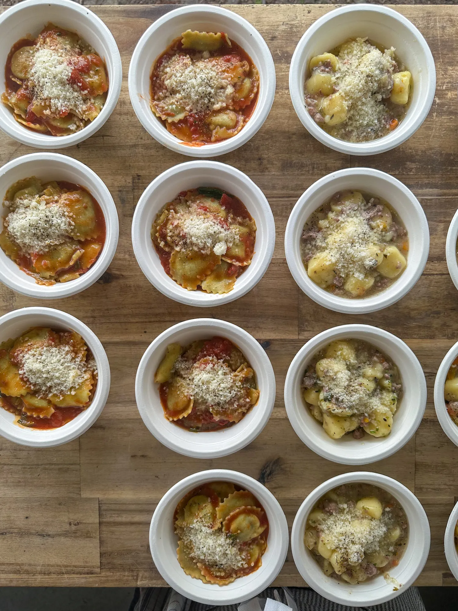 Amaranto's Bis di Primi — ravioli in tomato and basil sauce alongside gnocchi with white lamb ragù, plated and ready to serve at a wedding