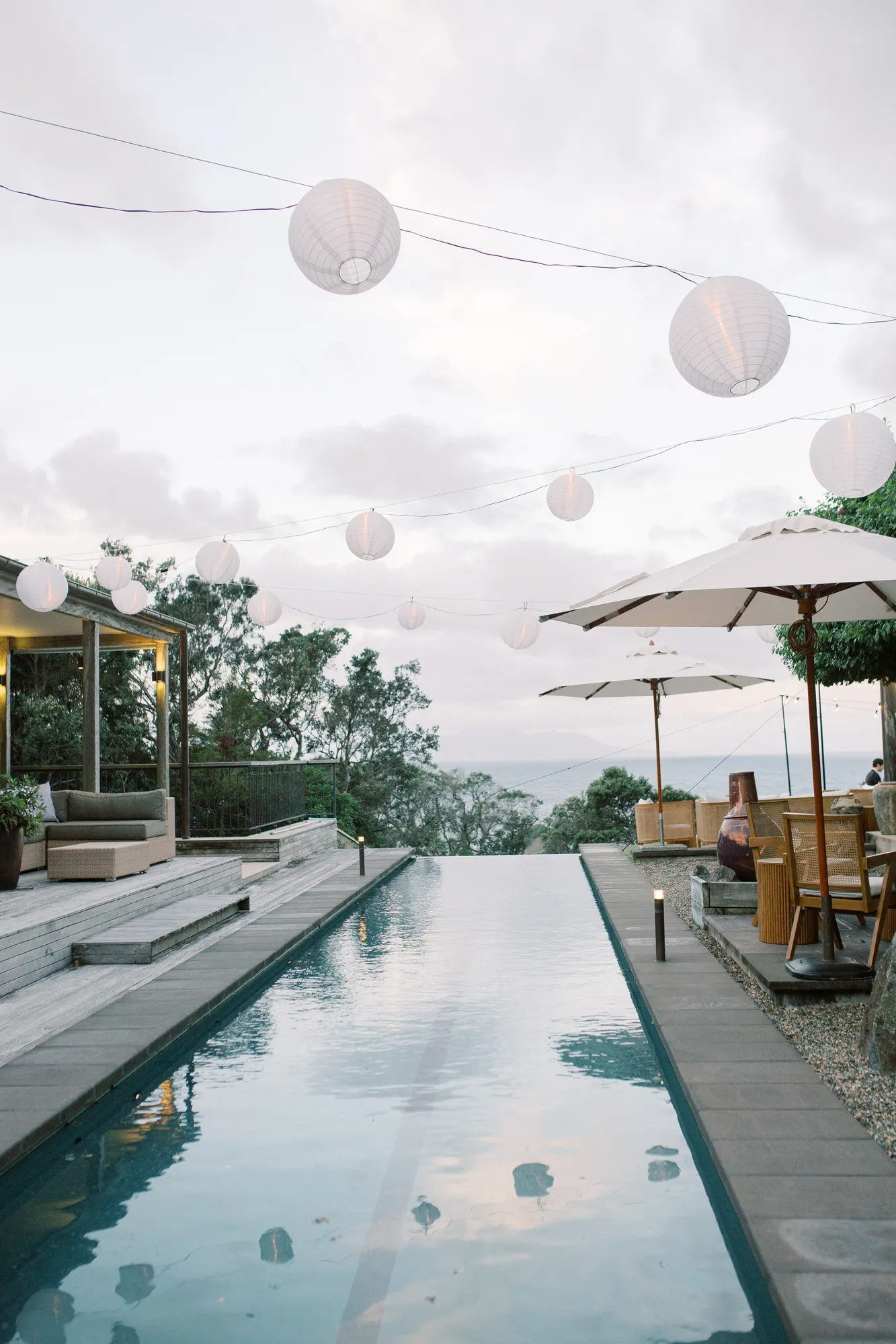 The pool terrace at Ti Point with paper lanterns glowing softly at dusk, at Elle and Sam's wedding