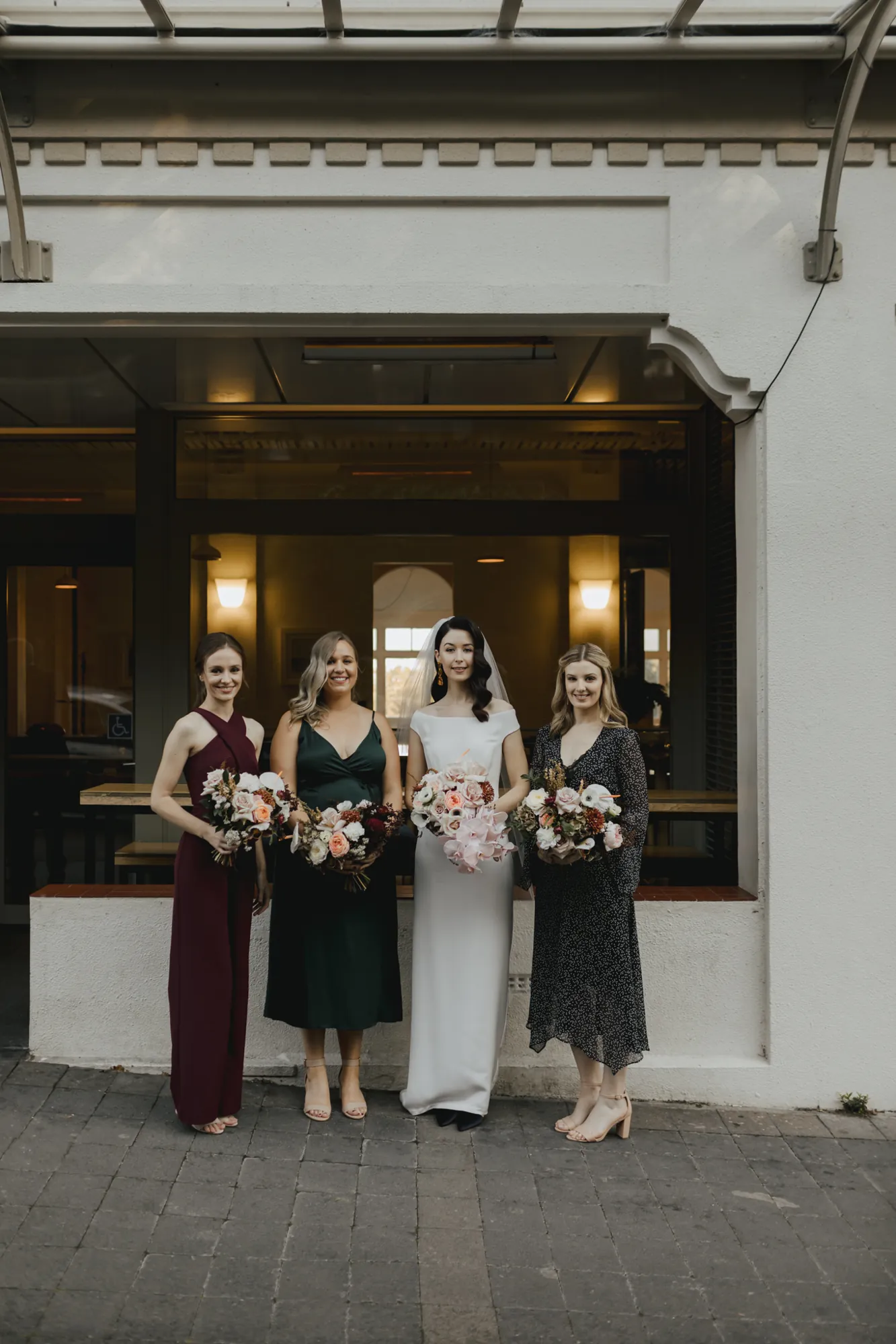 Lily with her three bridesmaids holding autumnal bouquets outside French Bay Yacht Club