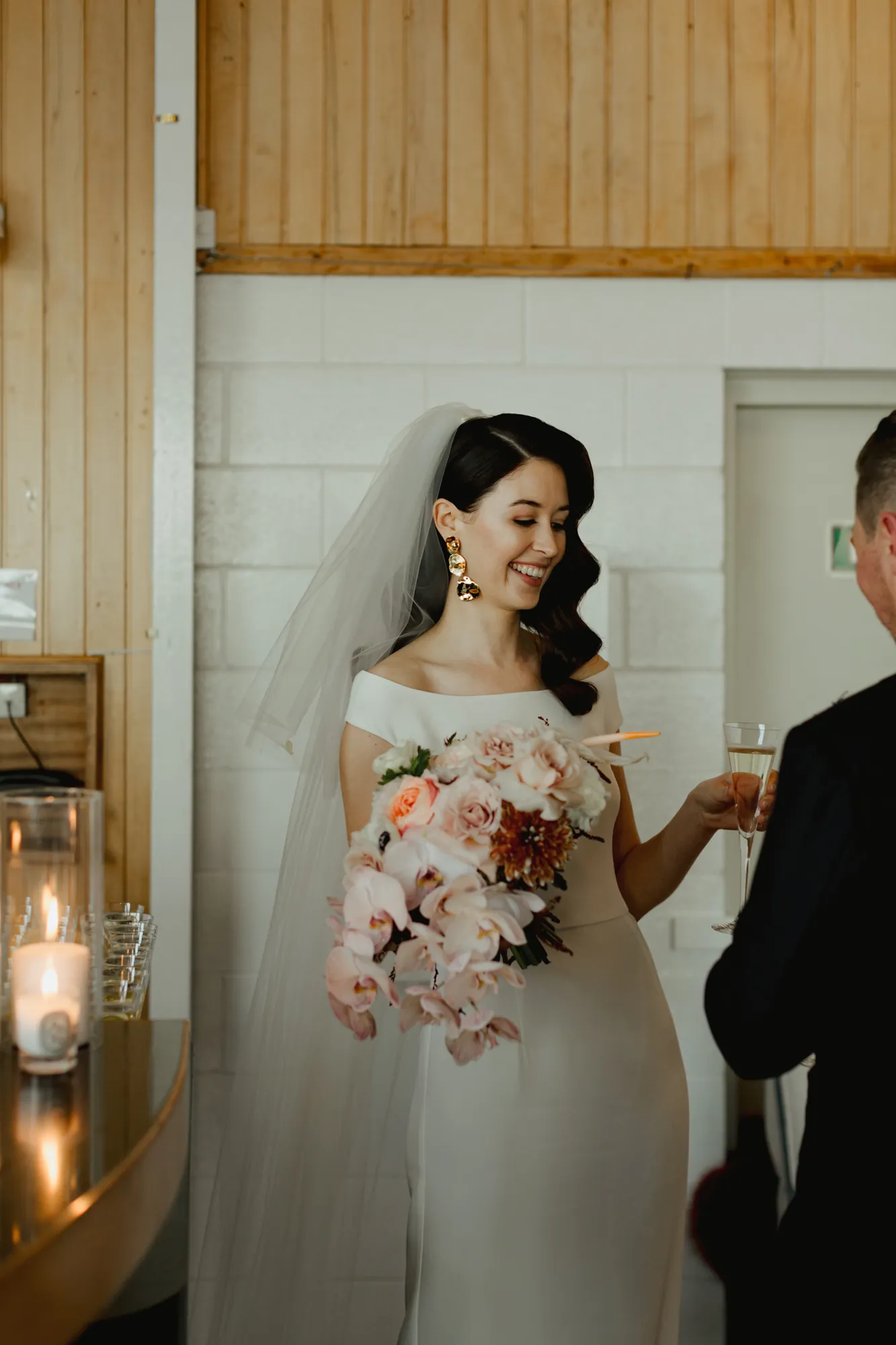 Lily laughing with a glass of champagne, holding her blush pink bouquet