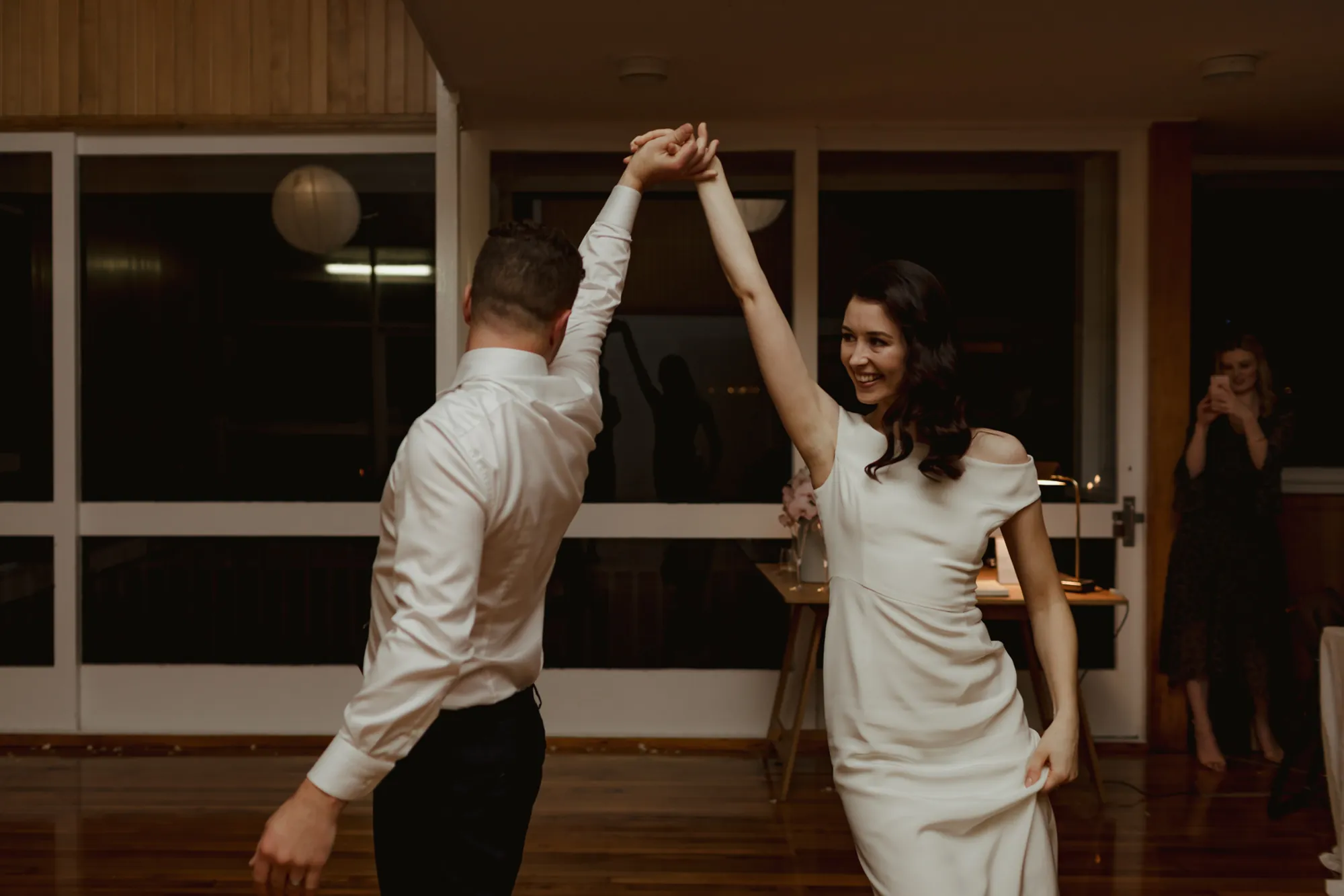 Lily and Dylan dancing their first dance, Lily smiling as she twirls under his arm