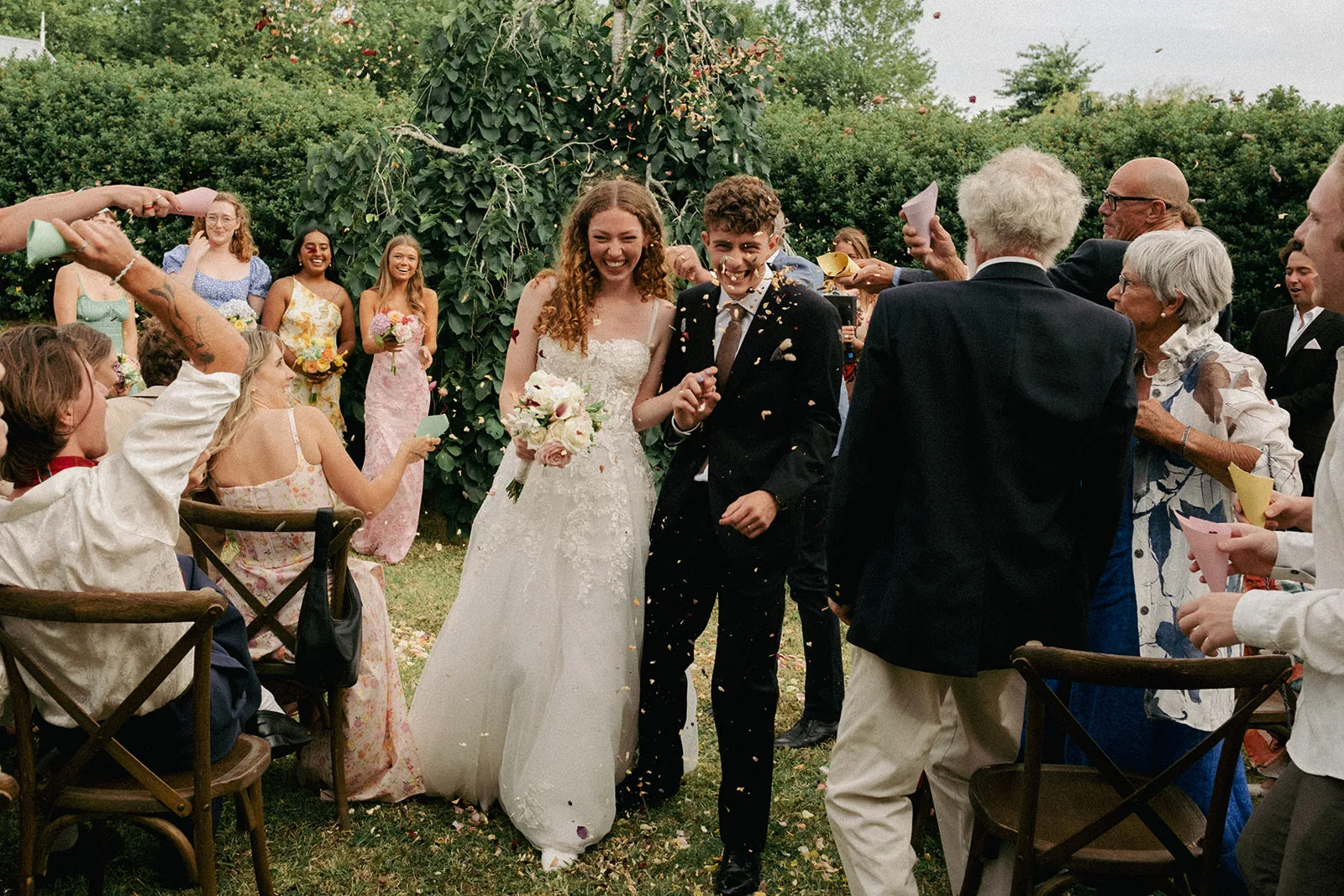 Phaedra and Isaac walk through a shower of confetti after their ceremony at the family home in Matakana
