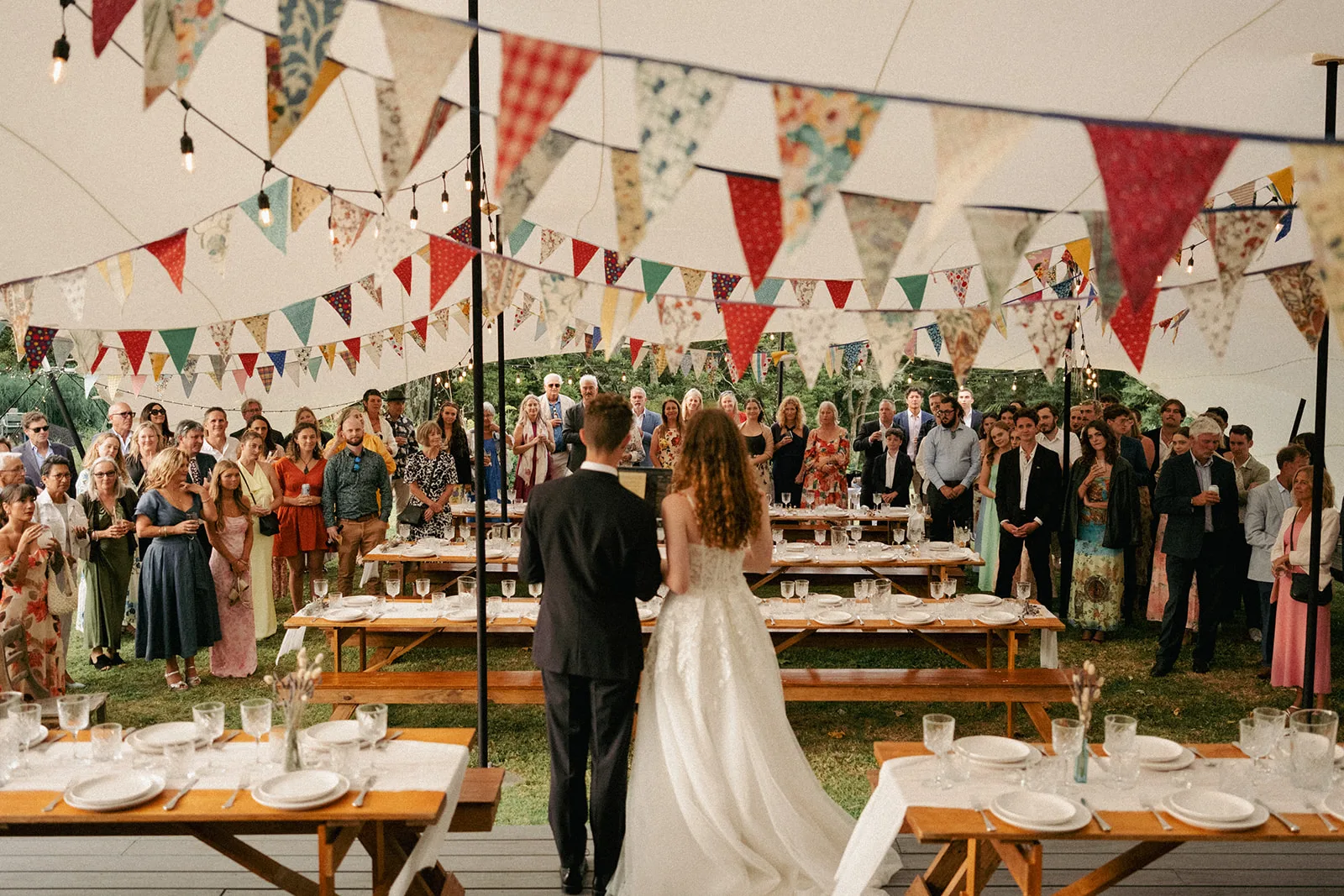 The wedding reception under a tent with bunting at Phaedra and Isaac's family home in Matakana
