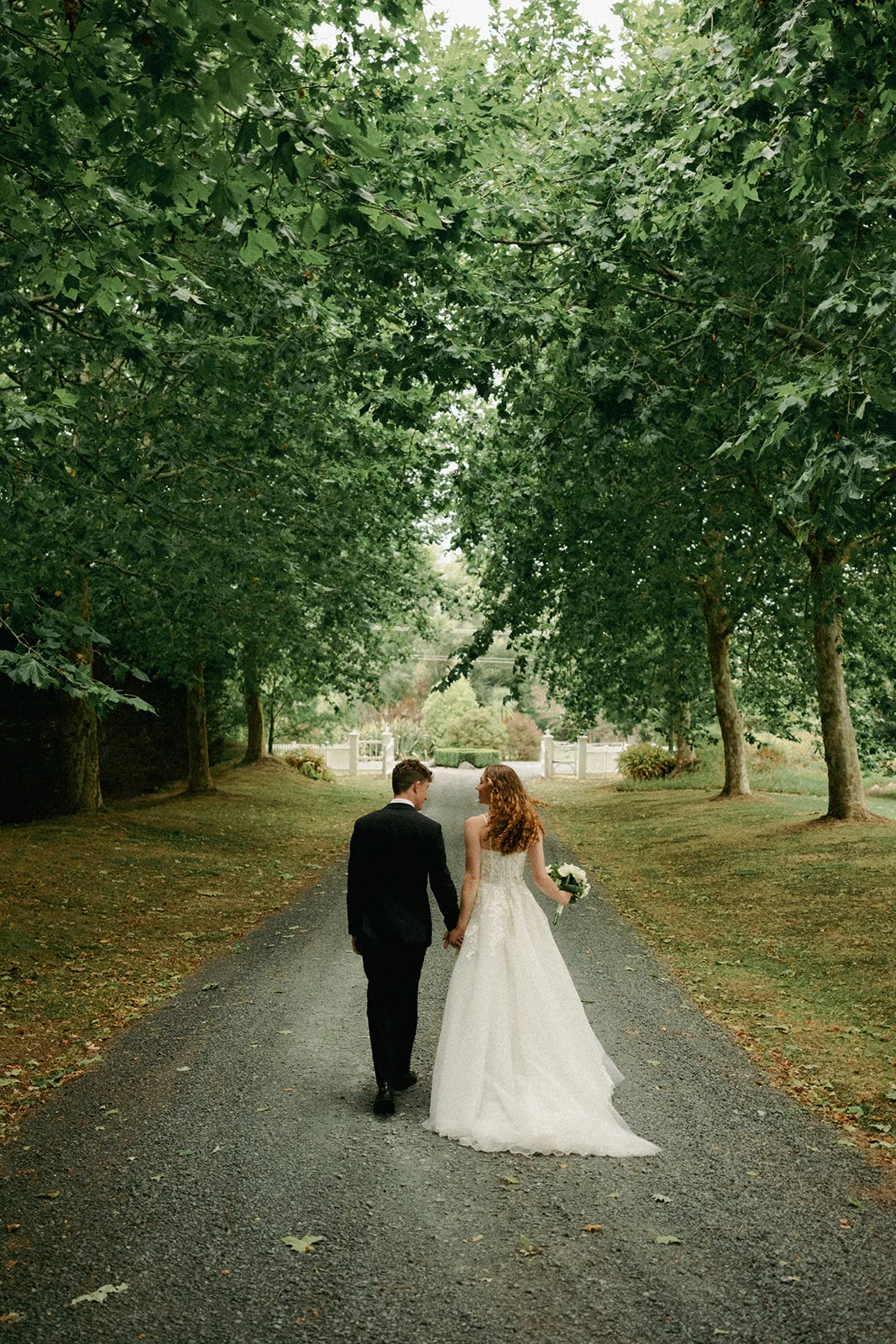 Phaedra and Isaac walk together down the tree-lined driveway at the family home in Matakana