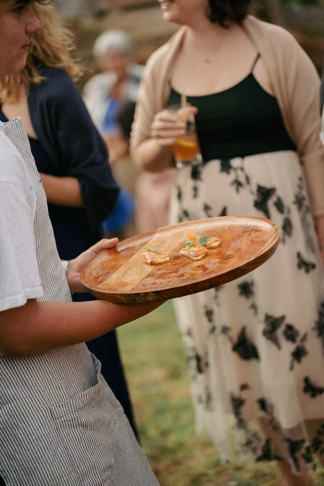 A guest receives a canapé from an Amaranto waiter on the lawn at Phaedra and Isaac's wedding