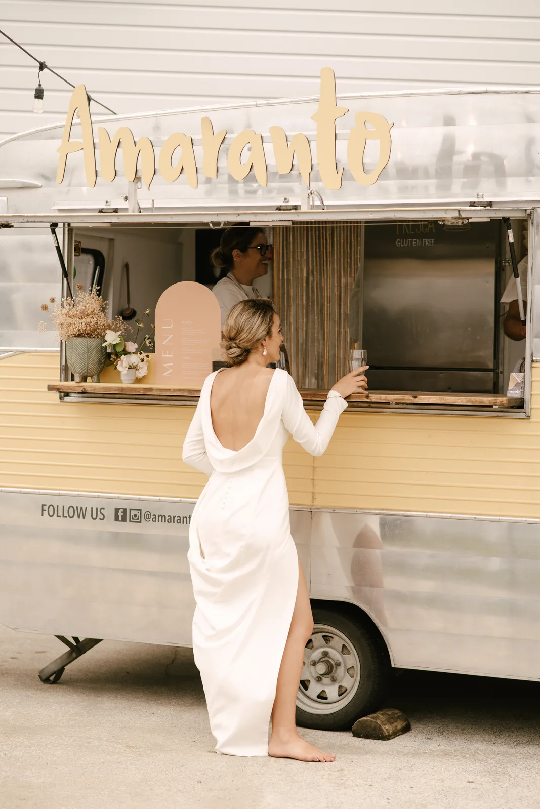 Sandi, the barefoot bride, at the Amaranto caravan window at her wedding at Whangaumu Bay, Tutukaka Coast